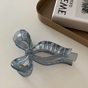 Close-up of translucent blue bow hair claw clip on minimalist beige desk setup