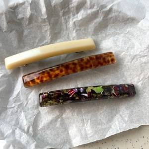 Detailed close-up of three patterns hair barrettes in beige, tortoise, and floral resin