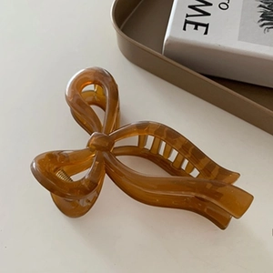 Close-up of amber resin bow hair claw clip showing glossy finish and grip teeth