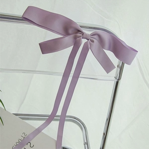 Gros plan d'une élégante pince à cheveux avec nœud en satin violet clair sur une chaise