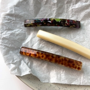 Detailed view of three acetate hair clips with tortoiseshell, cream, and floral patterns