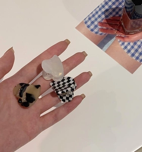 Close-up of three mini heart-shaped hair claws in tortoiseshell, pearl white, and checkerboard