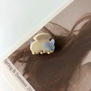 Vue détaillée d'une pince à cheveux crème avec papillon bleu clair et accents en cristal