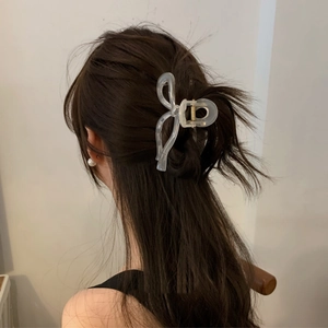 Detailed back view of a large clear bow hair claw clip styled on dark brown wavy hair