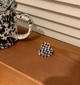 Close-up of heart-shaped checkerboard hair claw clip on a minimalist wooden table