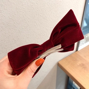 Dettaglio ravvicinato di un grande fiocco per capelli in velluto rosso con clip in metallo
