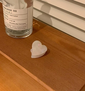 Macro detail of a pearlescent heart-shaped hair claw clip on a minimalist wooden table