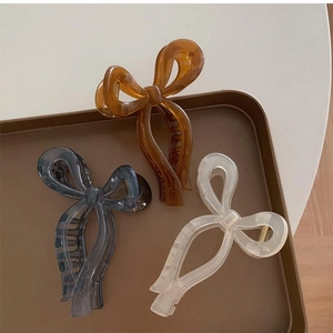 Three-piece set of elegant bow hair claws in amber, grey, and creamy white resin