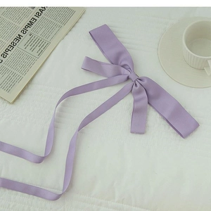 Pince à cheveux élégante en satin violet avec de longs rubans sur fond de tissu blanc