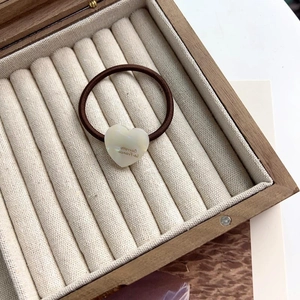 Élastique à cheveux marron avec breloque cœur en perle dans un écrin à bijoux velours