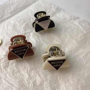 Close-up of three mini resin hair claws in black, brown and cream with gold lettering