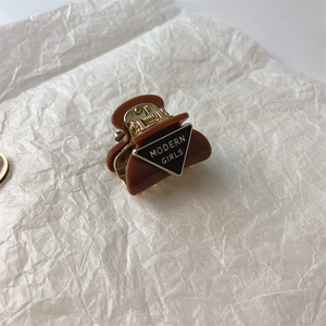 Detail view of small caramel brown resin hair claw with MODERN GIRLS text logo