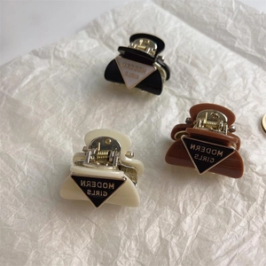 Three elegant small claw clips in black, beige, and brown with modern text detail
