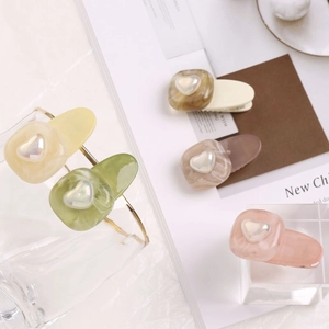 Détail de pinces à cheveux coeur aux couleurs bonbon et motifs marbrés sur fond blanc