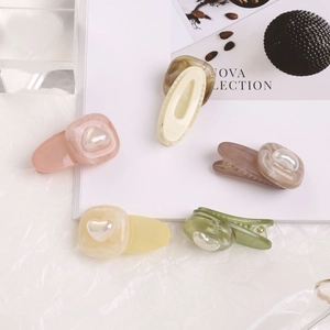 Détail de barrettes à cheveux aux couleurs bonbon avec motifs marbrés et perles de cœur