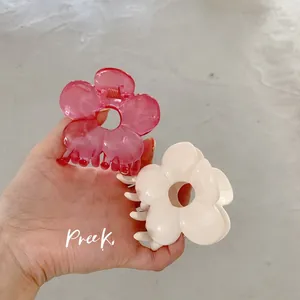 Dettaglio di fermagli per capelli a forma di fiore rosa e avorio traslucido tenuti in mano