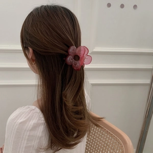 Dettaglio di un fermaglio per capelli a fiore rosa indossato su sfondo classico