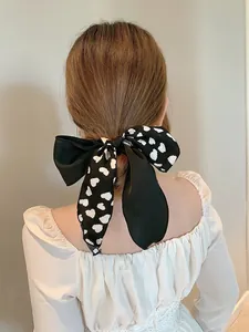 Detailaufnahme einer großen schwarzen Satin-Haarschleife mit weißen Herzmustern