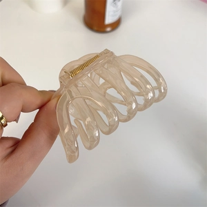 Close-up of large cream-colored hair claw clip with gold spring for thick hair