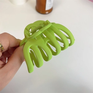 Detail of neon green matte hair claw clip held by hand to show large size and grip