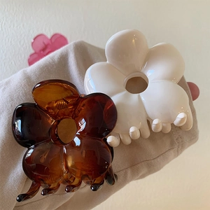 Detailed view of large acrylic flower hair claws in amber brown and ivory white