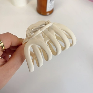 Handheld view of a large cream matte hair claw clip for thick hair styling and elegance