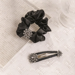 Detail of luxury black satin hair scrunchie and clip set with floral rhinestone accents