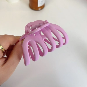 Close-up of a large matte pink hair claw clip for thick hair held in hand to show size