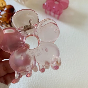 Dettaglio della pinza per capelli a fiore rosa traslucido con petali tondi e molla