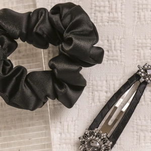 Detail of elegant black satin scrunchie and luxury rhinestone floral hair clip