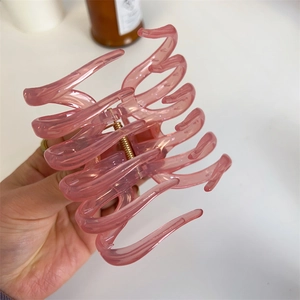 Detail of large translucent pink hair claw clip showing its strong gold metal spring