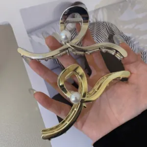 Macro detail of large gold and silver metal hair claws with elegant pearl embellishment