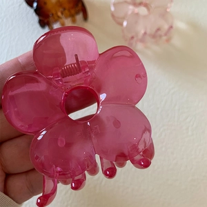 Close-up of translucent pink acrylic camellia flower hair claw clip with spring grip