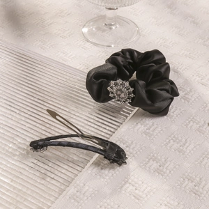 Detail view of black satin scrunchie with crystal decoration and matching hair clip set