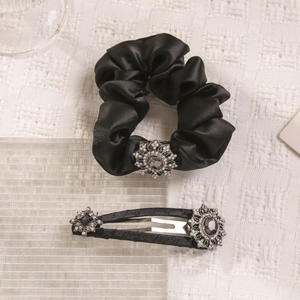 Detail shot of black satin scrunchie and hair clip with rhinestone floral ornaments