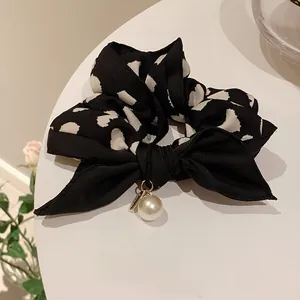 Nahaufnahme von elegantem Haargummi mit Herzmuster, Schleife und Perlenanhänger