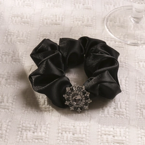 Close-up of black satin scrunchie with a sparkling sunflower rhinestone centerpiece