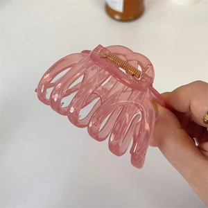 Pink transparent hair claw clip for thick hair with gold spring in a hand-held view