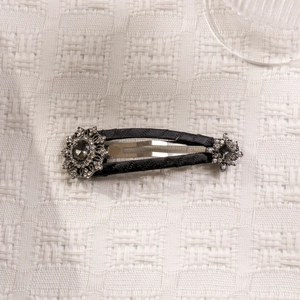 Detailed view of a black satin hair clip with sparkling rhinestone flower embellishments
