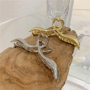 Dettaglio ravvicinato di fermagli per capelli in metallo oro e argento con cuore intagliato