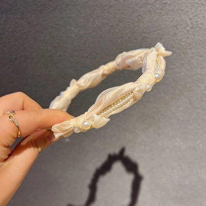 Détail d'un serre-tête en satin champagne orné de perles et de strass brillants