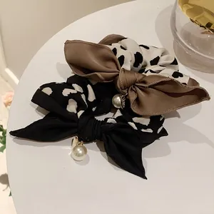 Nahaufnahme von gepunkteten und Leoparden-Scrunchies mit eleganten Perlenanhängern