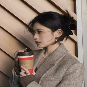 Detail of a large black acetate bow hair claw clip worn on a model in a casual outdoor setting