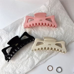 Detailed view of oversized acetate claw clips in pink, black, and beige colors