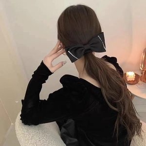 Detail showing elegant black satin bow hair clip with pearls and rhinestones on hair