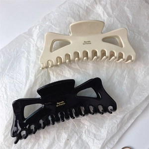 Detail of French style large hair claws in black and beige with gold logo lettering