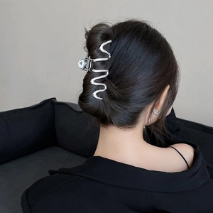 Silver wavy metal shark hair claw clip shown on model hair from a 45-degree angle