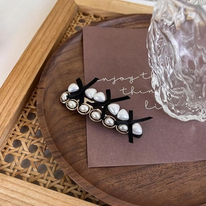 Close-up of vintage metal hair clip with pearls, heart beads and black bows decor