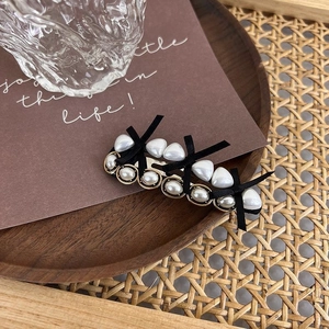 Detail of vintage pearl hair clip with black fabric bow and golden metal base