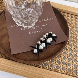 Detail of vintage heart-shaped pearl hair clips with black bows on a wooden display